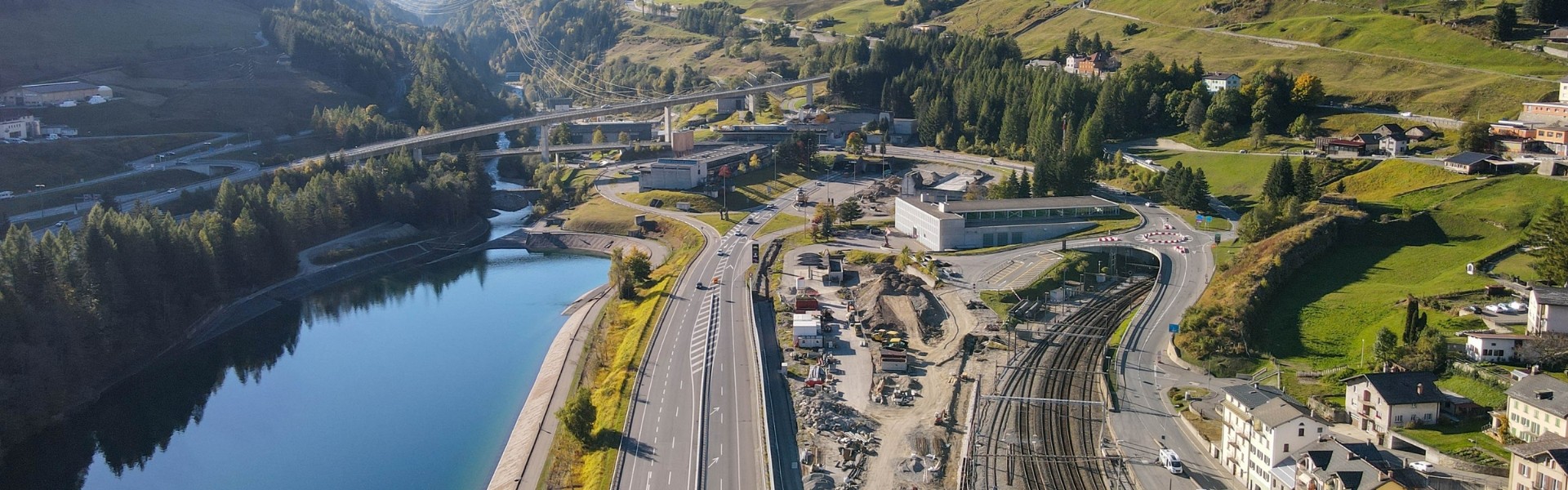 Aerial view of a highway, railway, and a river surrounded by green hills.