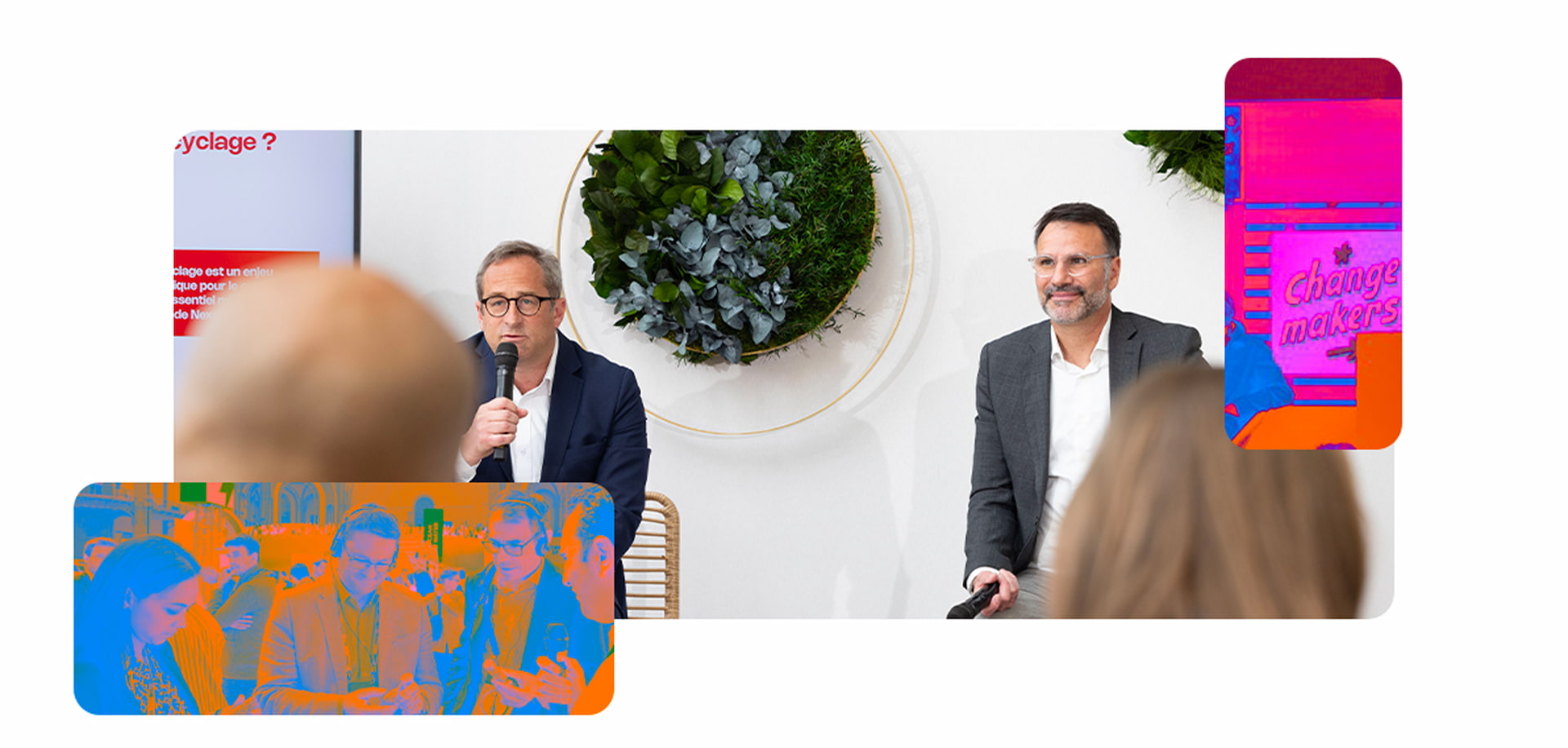 Two speakers at a professional event discussing renewable energy with a backdrop of plants.