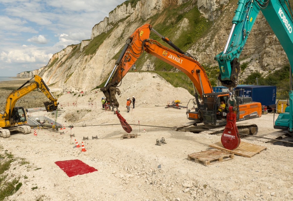 Construction site with excavators and workers near chalk cliffs