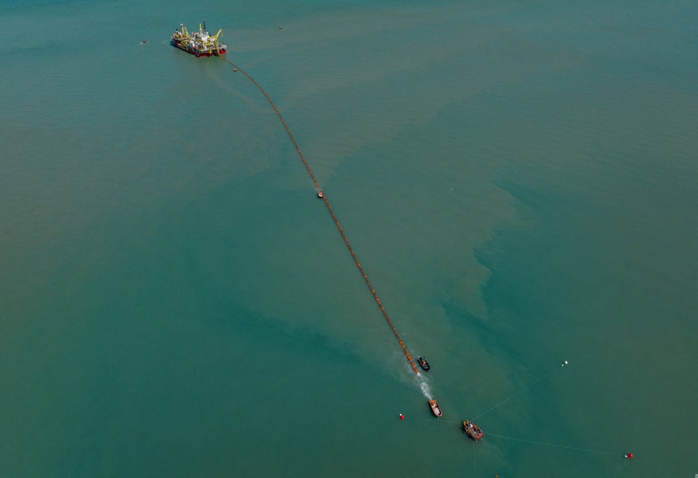 Aerial view of fishing boats connected to an offshore platform, with calm turquoise waters.