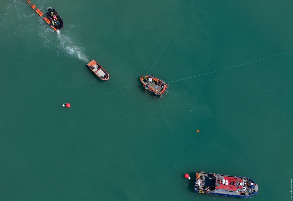 Aerial view of several boats on calm water with floating buoys.
