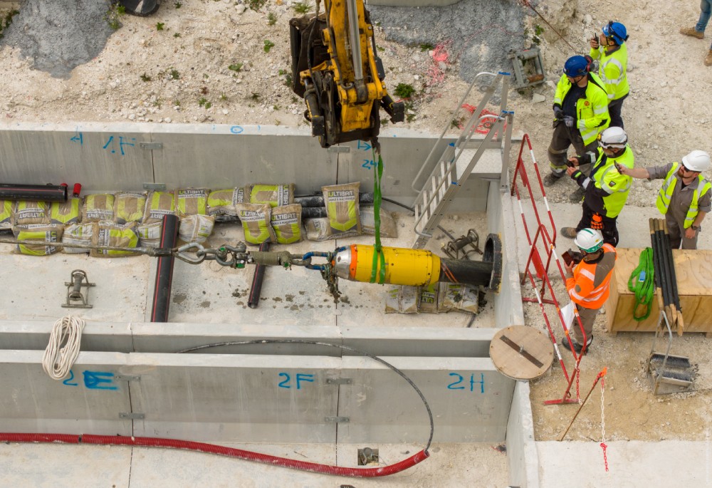 Construction site with workers handling machinery and materials.