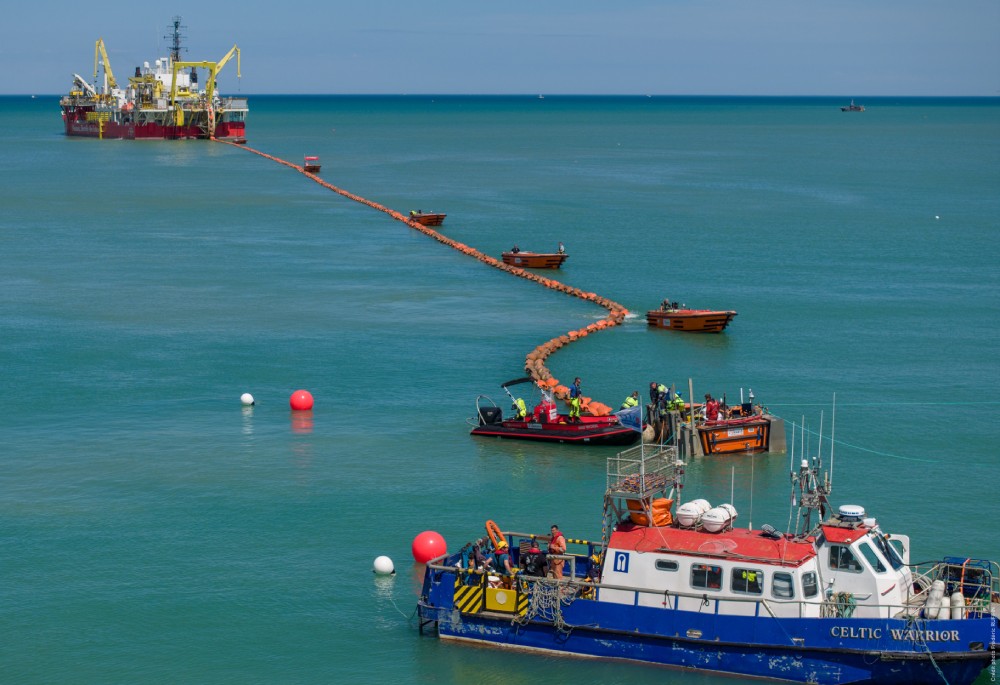 A vibrant seascape showing boats and a large ship involved in marine operations.