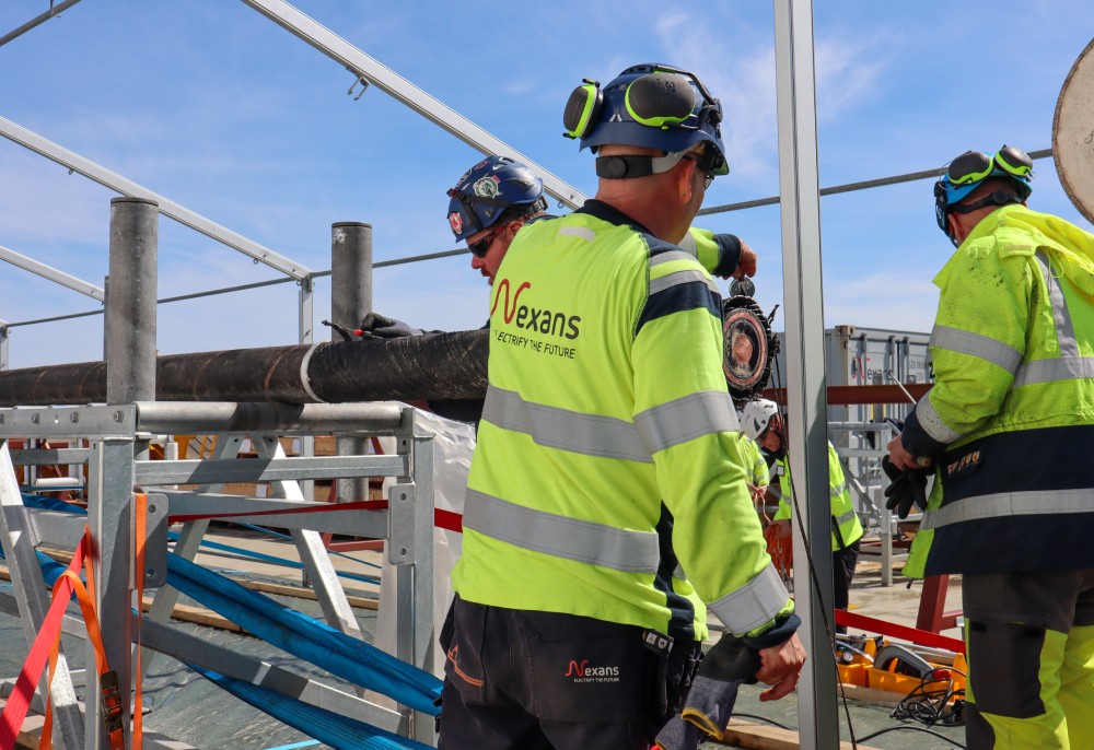 Team of construction workers in safety gear handling equipment at a construction site.