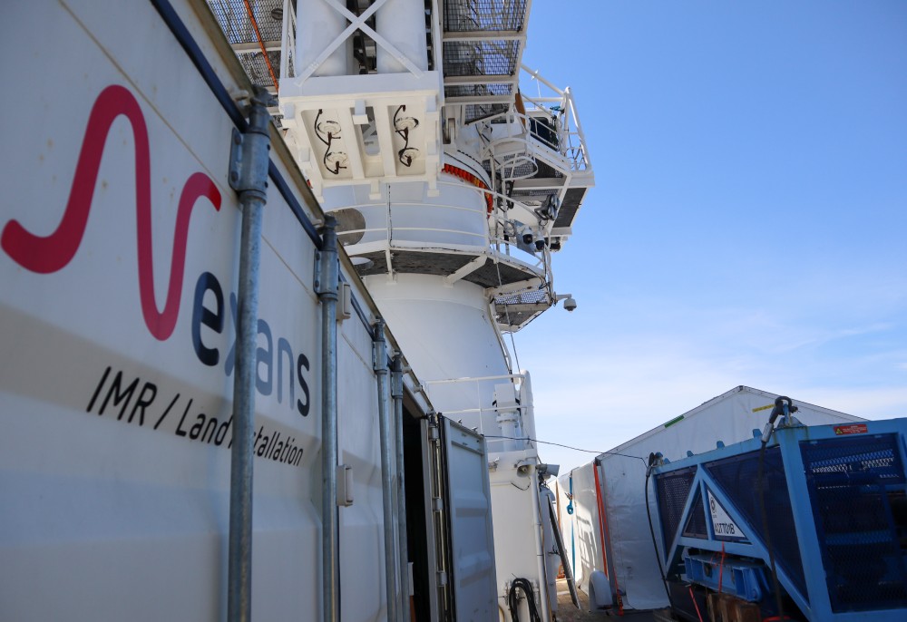 View of a large vessel's structure with equipment on deck under a clear blue sky.