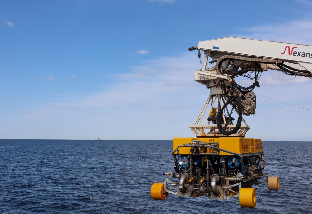 Underwater robot deploying from ship over ocean waters.