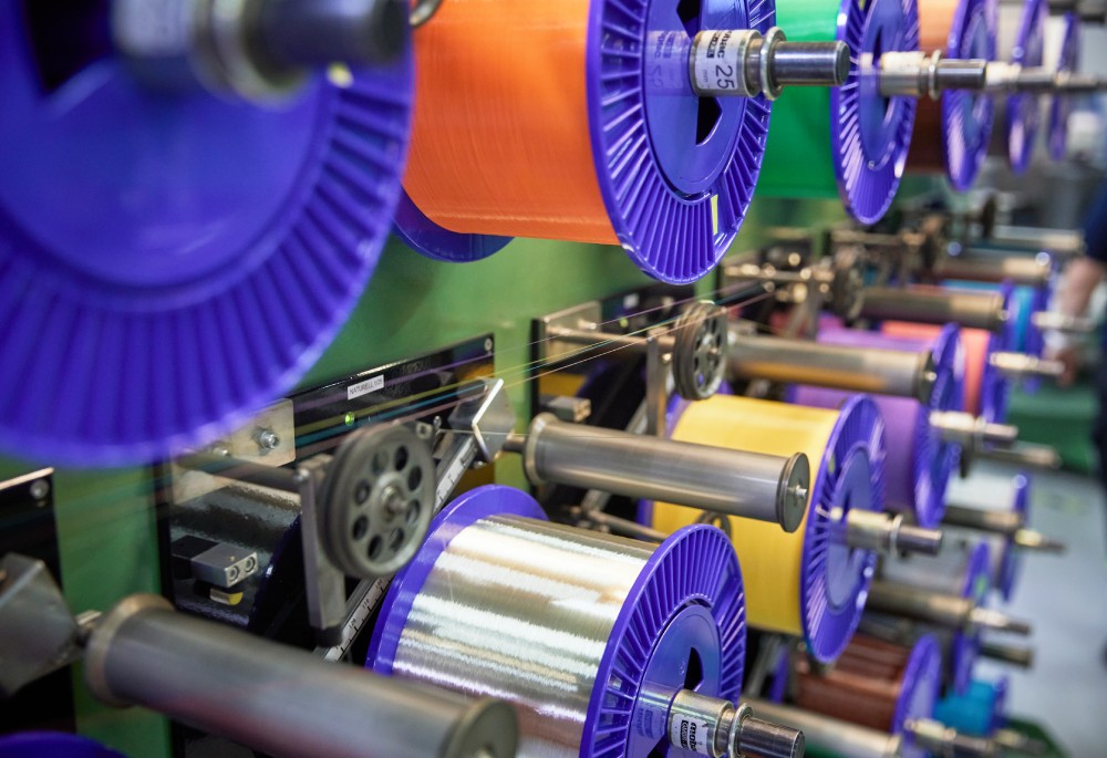 Colorful spools of thread arranged on a machine in a textile manufacturing setting